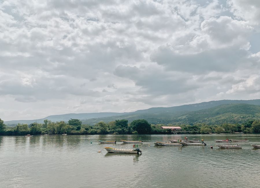 Tranquil scene of boats on Grijalva River with lush Mexican mountains in the background.