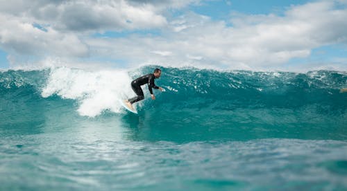 Man in Black Wet Suit Surfing on Sea Waves