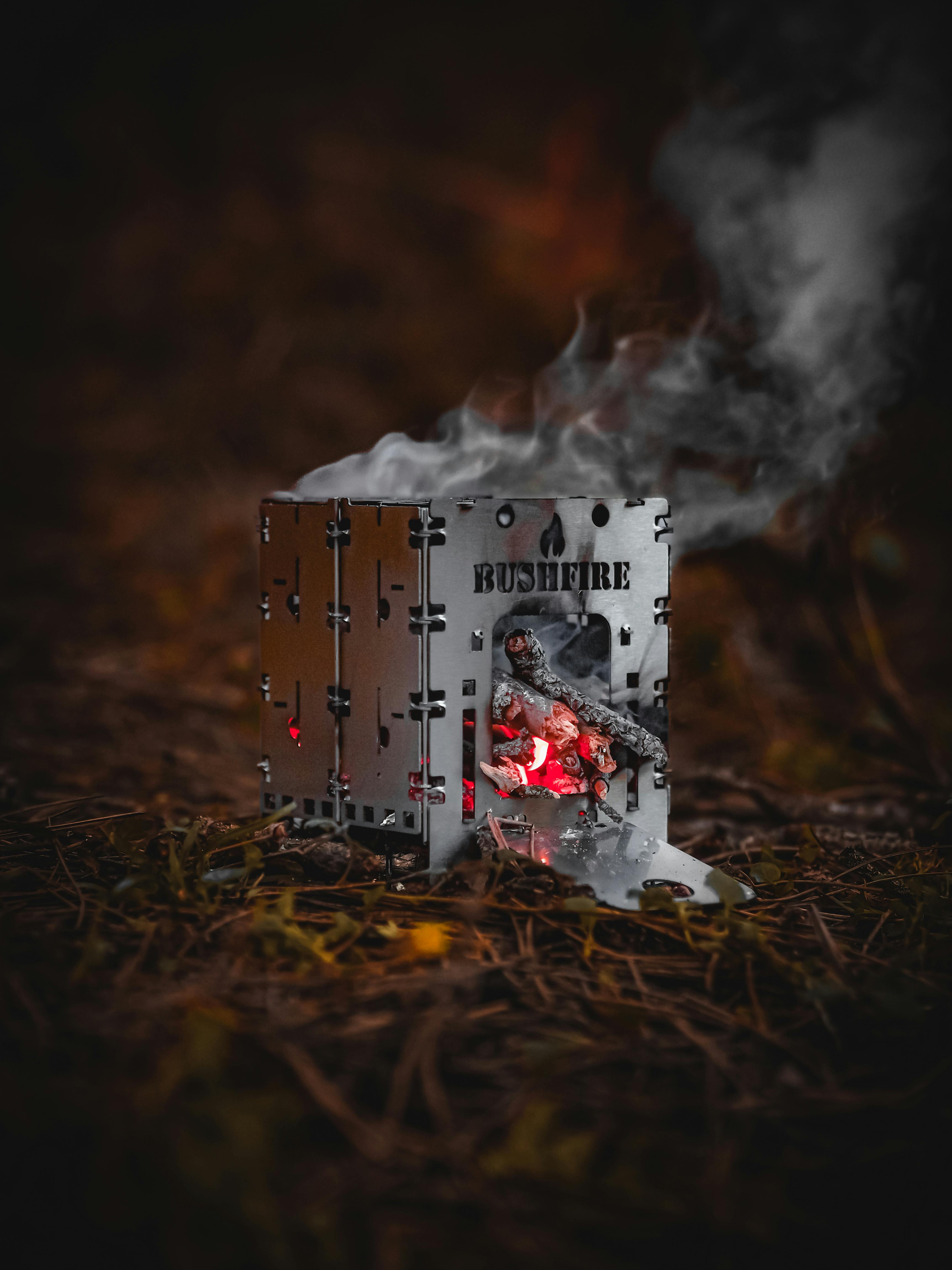 Close-up of a stainless steel camp stove with smoke, ideal for camping and hiking.