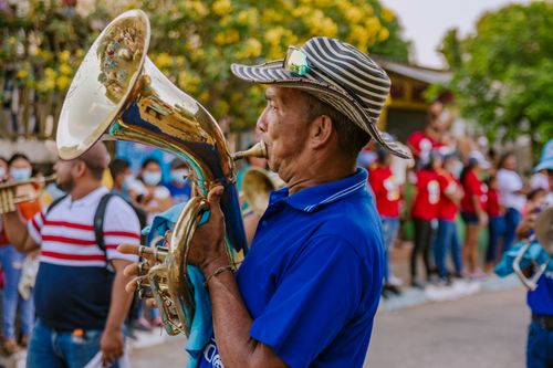 Free Elderly musician playing brass instrument in a lively Colombian parade, adding festive spirit to city streets. Stock Photo