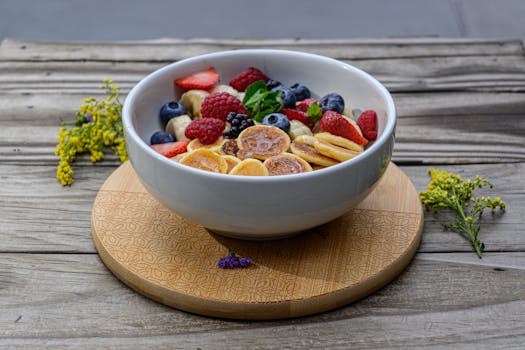 A vibrant breakfast bowl filled with fresh berries and banana slices on a wooden table.