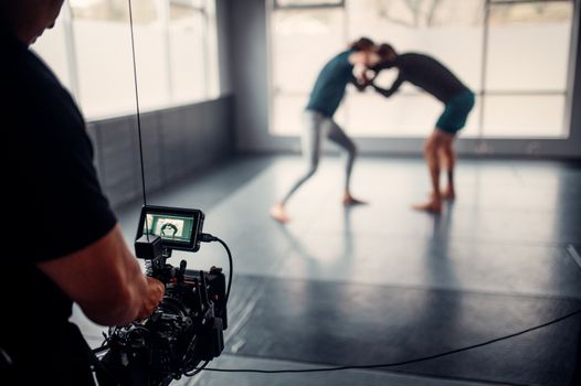 Capturing martial arts practice with professional filming equipment in a gym setting.