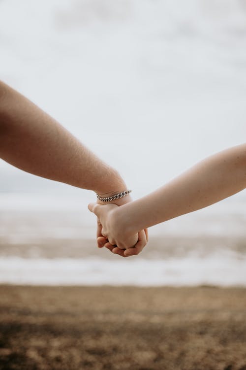Two People Holding Hands on the Beach 