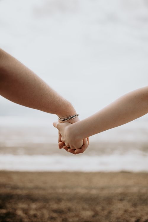 Free Two hands holding together against a serene beach backdrop, symbolizing unity and connection. Stock Photo