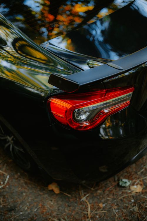 Free Close-up view of a black sports car featuring a modern red taillight, captured outdoors. Stock Photo