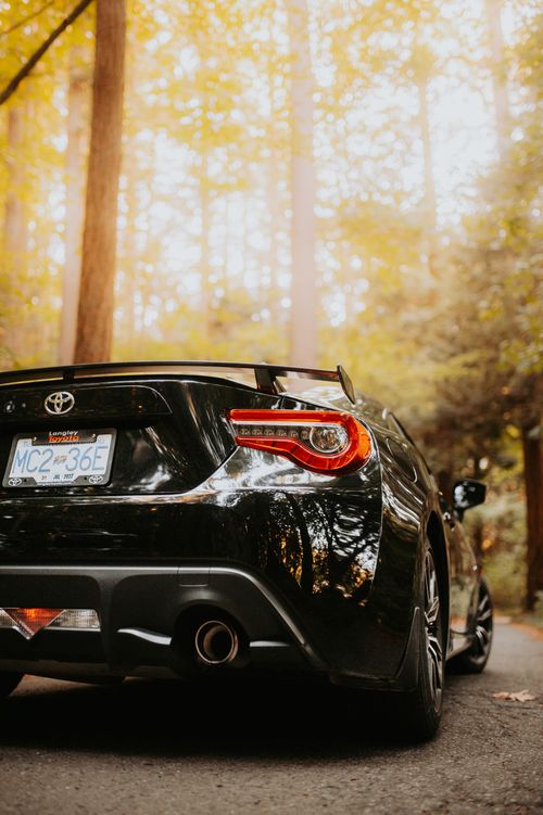 Free A close-up of a sleek black sports car, Toyota 86, parked in a serene forest setting. Stock Photo