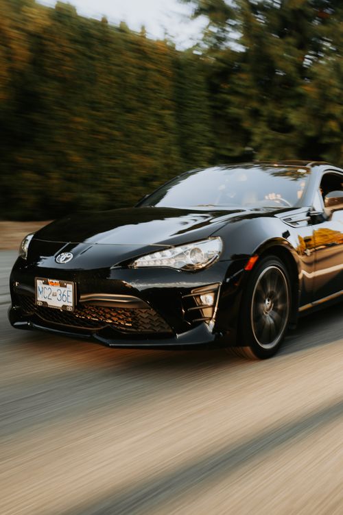 Free Dynamic close-up of a black sports car driving fast on the street, showcasing motion and speed. Stock Photo