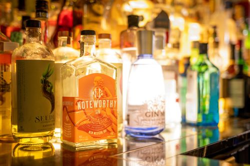 Free A colorful collection of gin bottles captured on a bar counter in warm lighting. Stock Photo