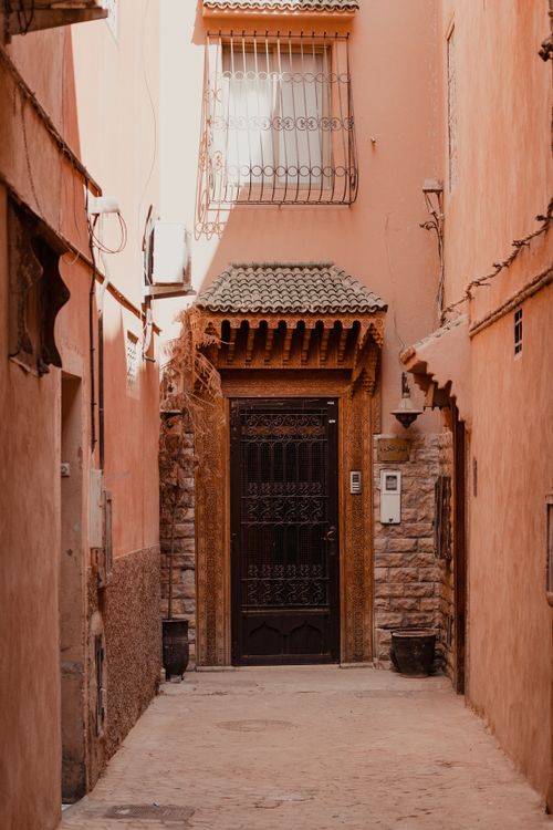 Free Explore a narrow Moroccan alley featuring traditional architecture and a detailed ornate door. Stock Photo