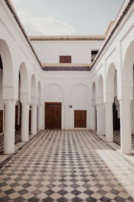 A stunning courtyard featuring arched columns and intricate tilework under a clear sky.