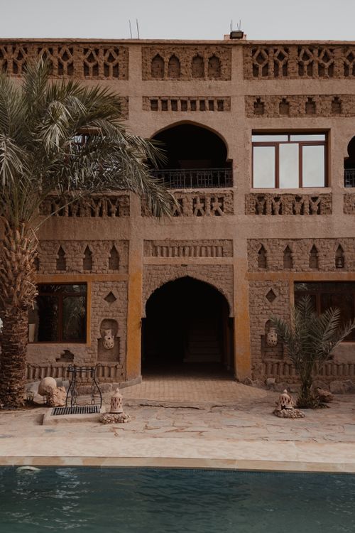Free Elegant Moroccan architecture featuring an ornate facade and inviting poolside view. Stock Photo