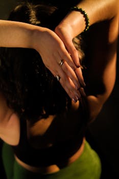 A woman in a yoga pose with hands elegantly above her head, highlighting grace and concentration.