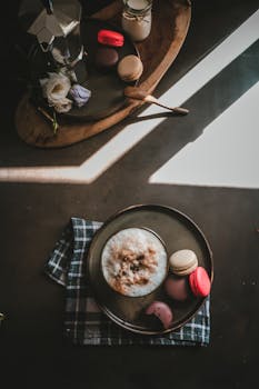 Elegant still life of cappuccino and macarons, captured with artistic flair in an indoor setting.