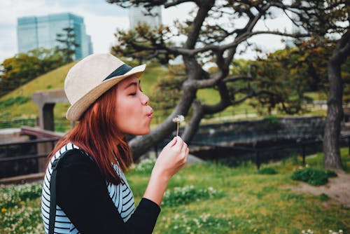 Femme Soufflant Et Tenant Une Fleur Blanche Près Des Arbres