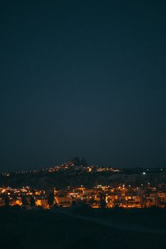A beautiful night view of a city with glowing lights under a dark starry sky, perfect for travel and architecture themes.