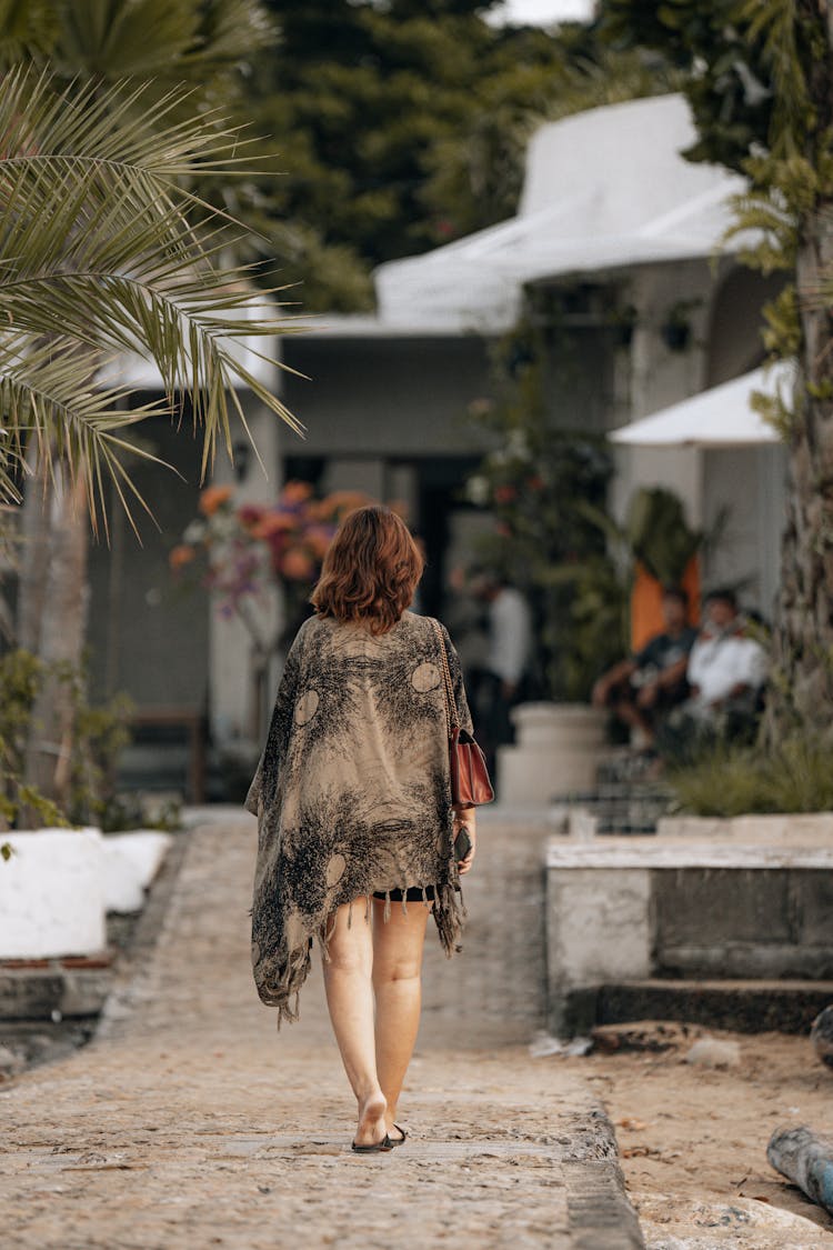 Back View Of A Woman With Shawl Walking On A Footpath