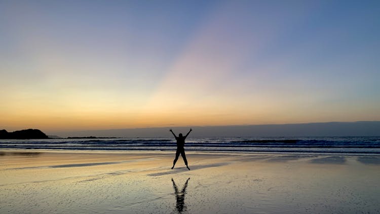 Silhouette Of A Person Jumping On Shore