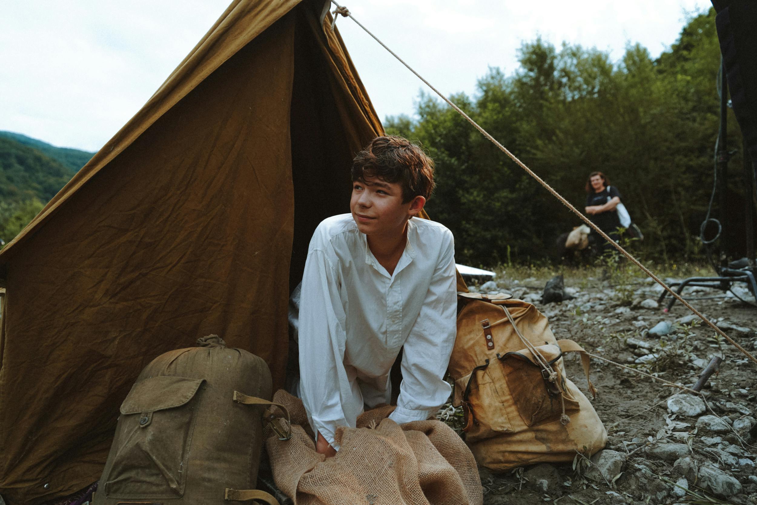 Boy Sticking His Head Out of a Tent in Mountains