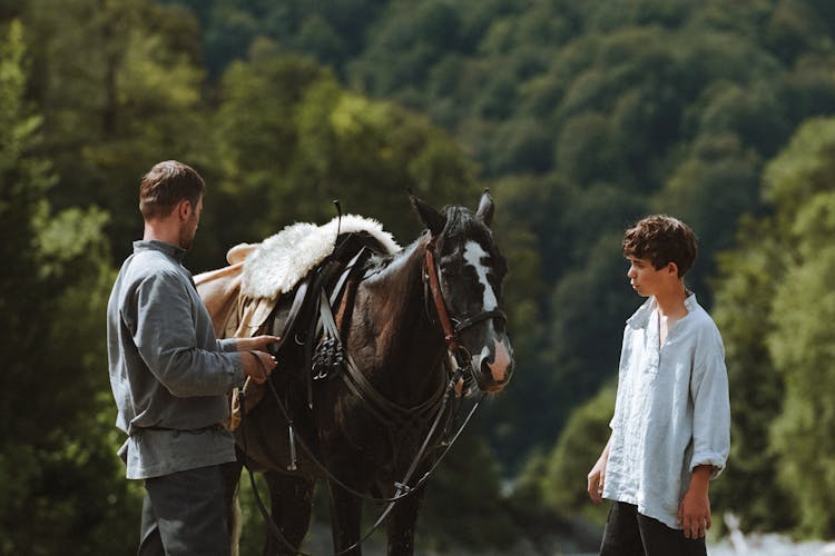 Man And Boy In Vintage Clothing Next To A Horse