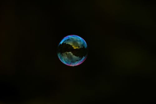 Free Vivid close-up of a solitary soap bubble reflecting light against a dark backdrop. Stock Photo