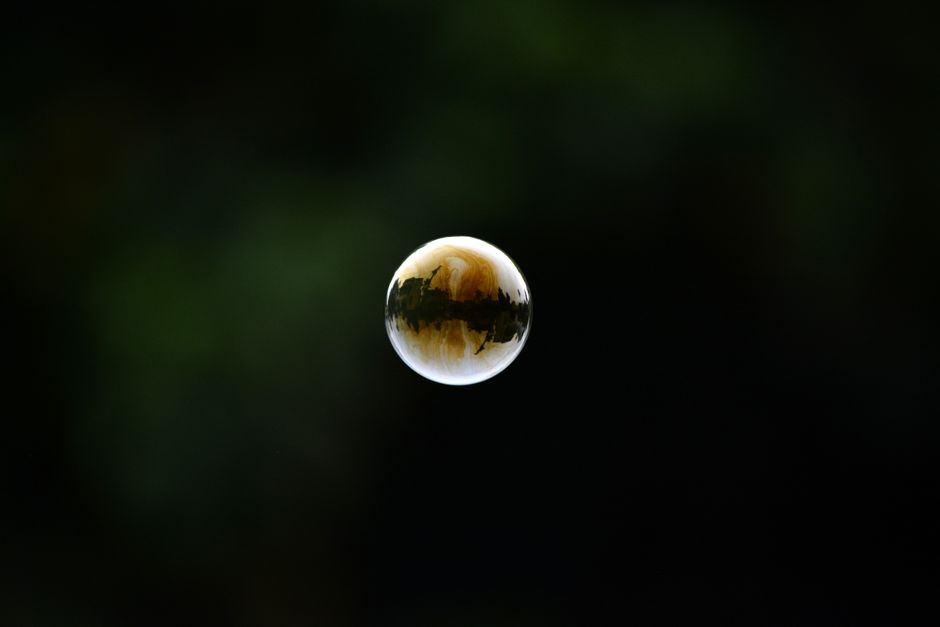A delicate bubble floating midair with a dark, unfocused background creating contrast.