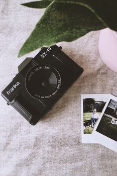 Close-up of a Franka NX-40 camera next to instant photos on a linen background.