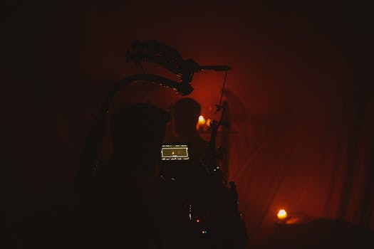 An atmospheric film set featuring a silhouetted cameraman filming by candlelight.
