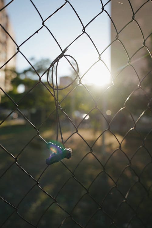 Lens Flare and Headphones Hanging on a Net Fence