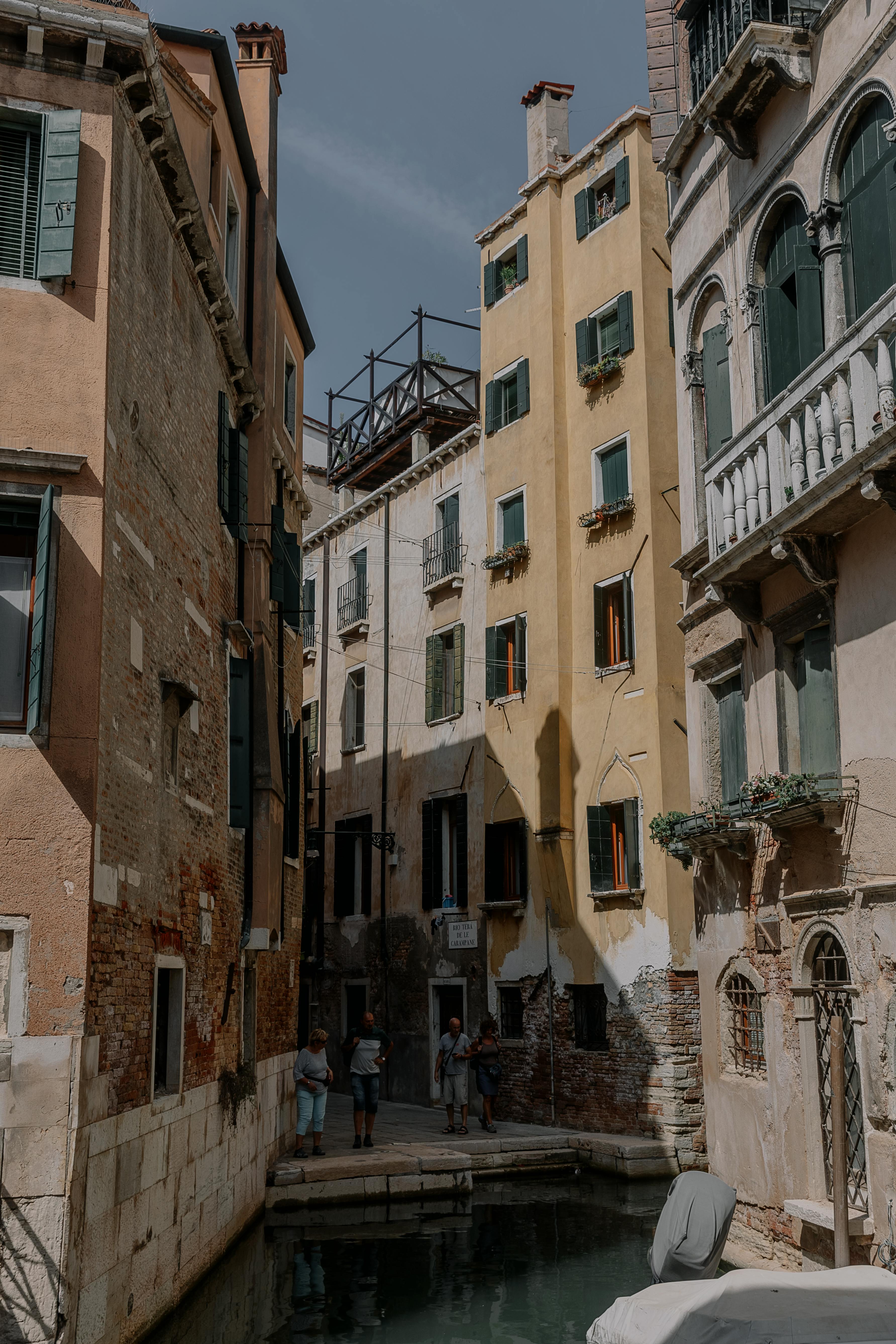 Explore the rustic charm of Venetian architecture lining a serene canal under a clear sky.