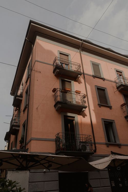 Free A corner view of a residential building with balconies and parasols, captured at dusk. Stock Photo