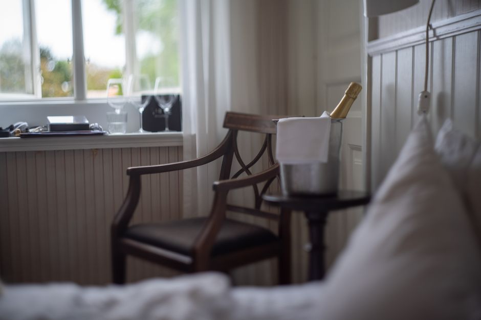 A serene indoor scene featuring a champagne bucket on a table beside a wooden chair.