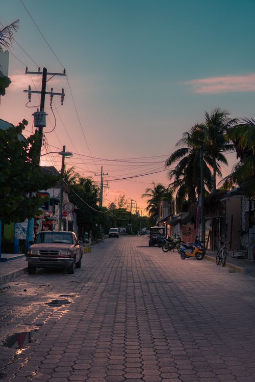 Free Early morning street in Isla Mujeres, Mexico, with cars and palm trees at dawn. Stock Photo