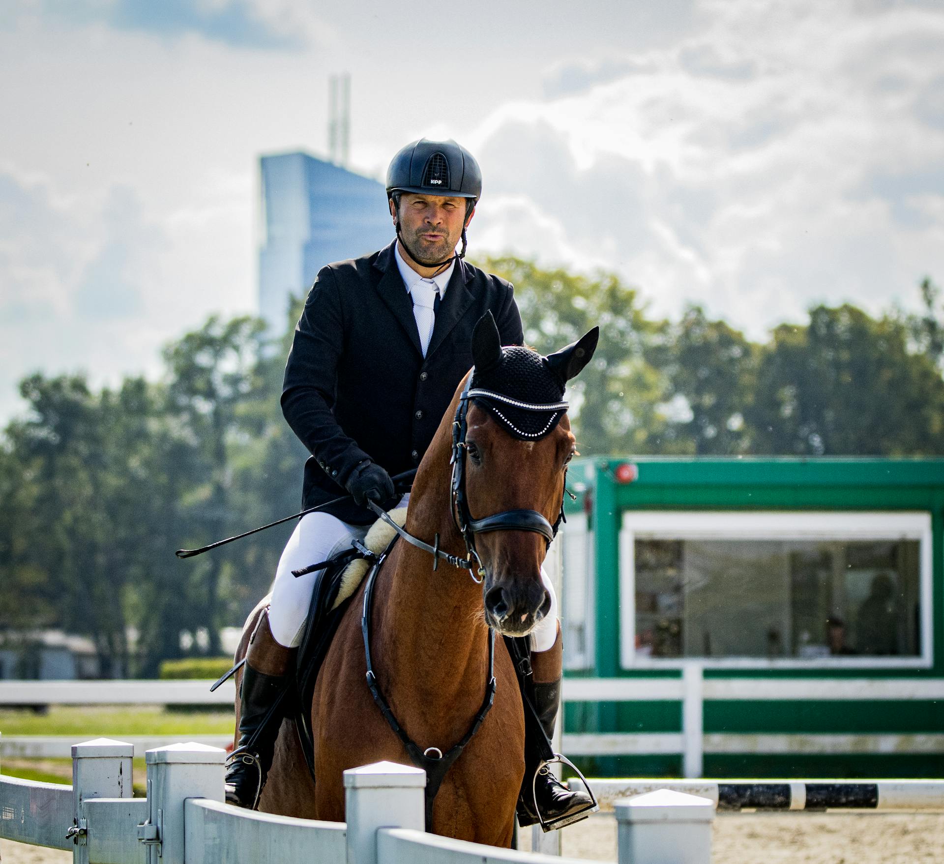 A skilled equestrian competitor riding a brown horse in an outdoor arena.