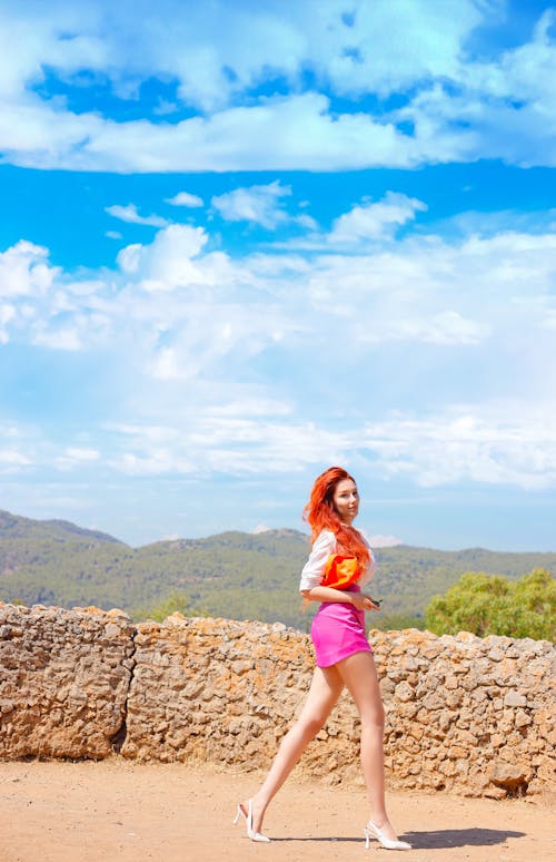 A Woman in White and Orange Shirt and Pink Shorts