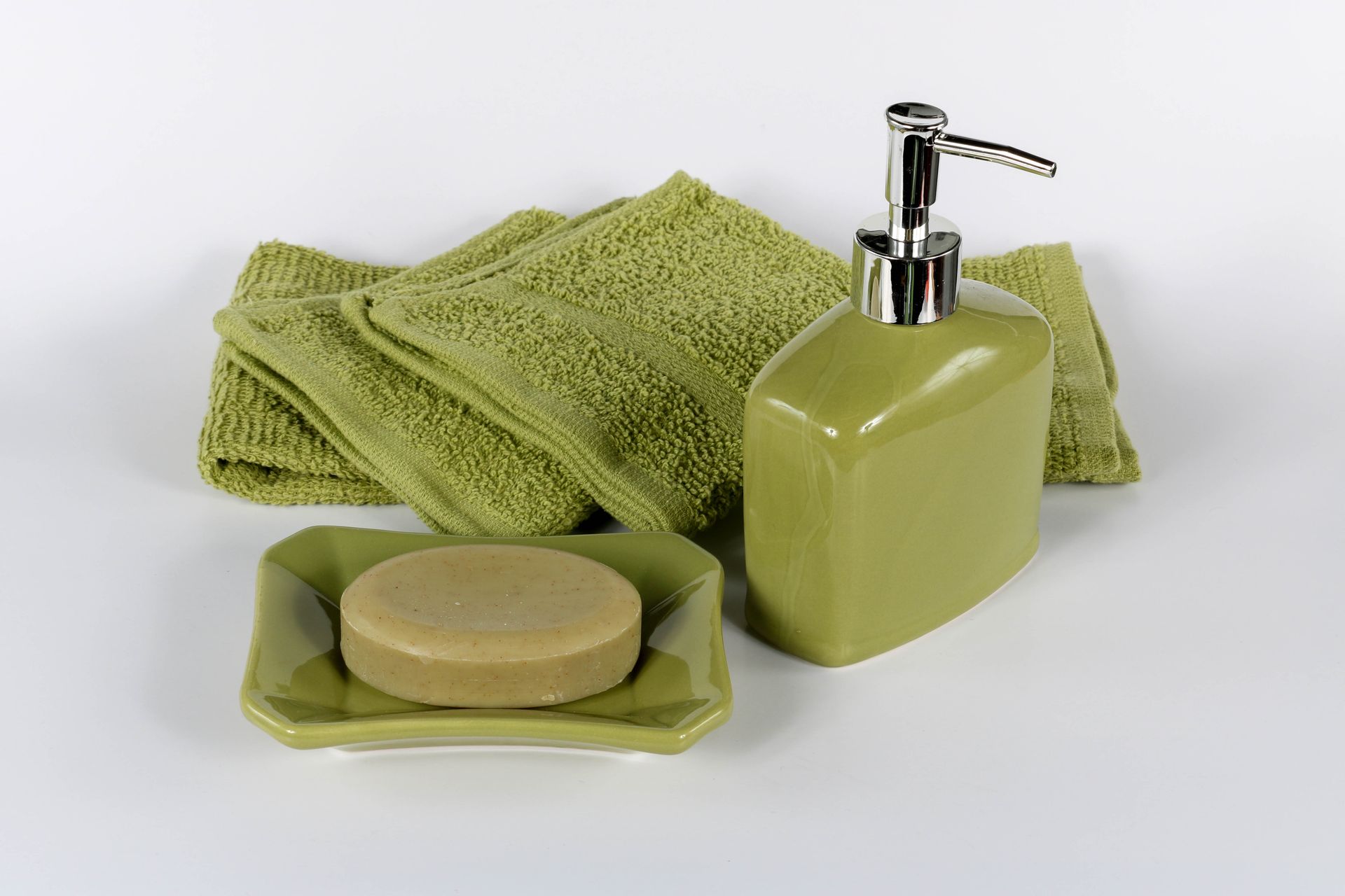 Stylish green bathroom essentials with towel, soap dish, and dispenser. Perfect for home decor.