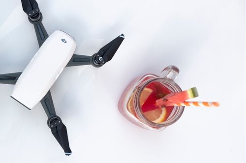 Free A top-down view of a drone and a refreshing fruit drink with lemon slices and a straw, set against a minimalist background. Stock Photo
