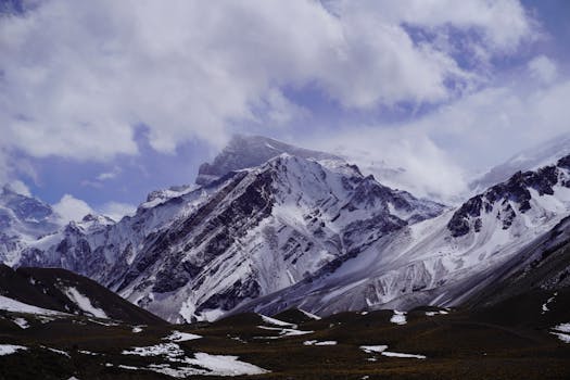 Experience the majestic snow-covered Andes Mountains under a cloudy sky in Argentina.