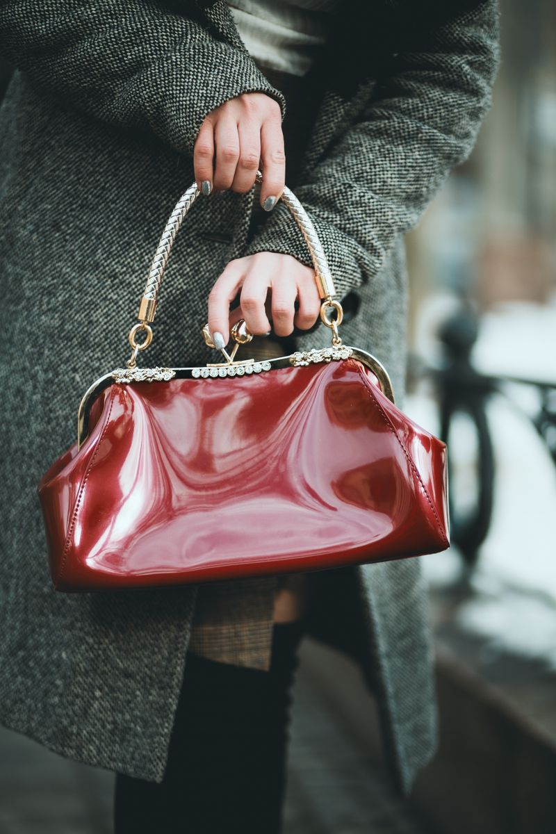 Stylish woman holding glossy red leather handbag