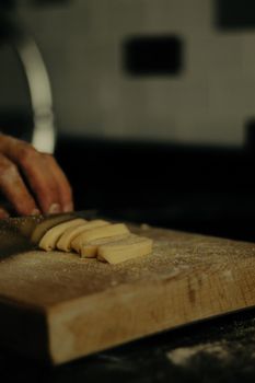 A chef slicing fresh fettuccine pasta on a wooden cutting board, showcasing homemade Italian cuisine.