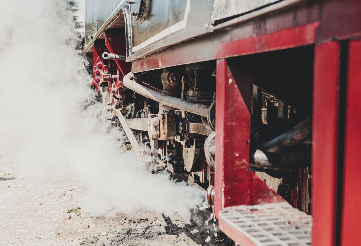A vintage steam locomotive releasing steam and smoke