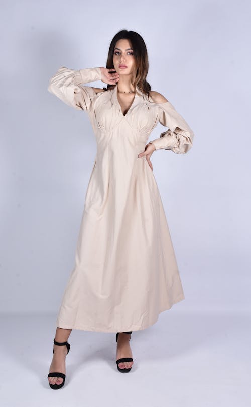 A Woman in Beige Long Sleeves Dress Standing while Posing at the Camera