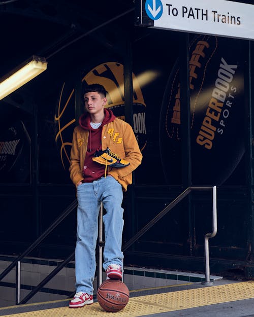 Stylish Young Man resting his Foot on a Basketball 