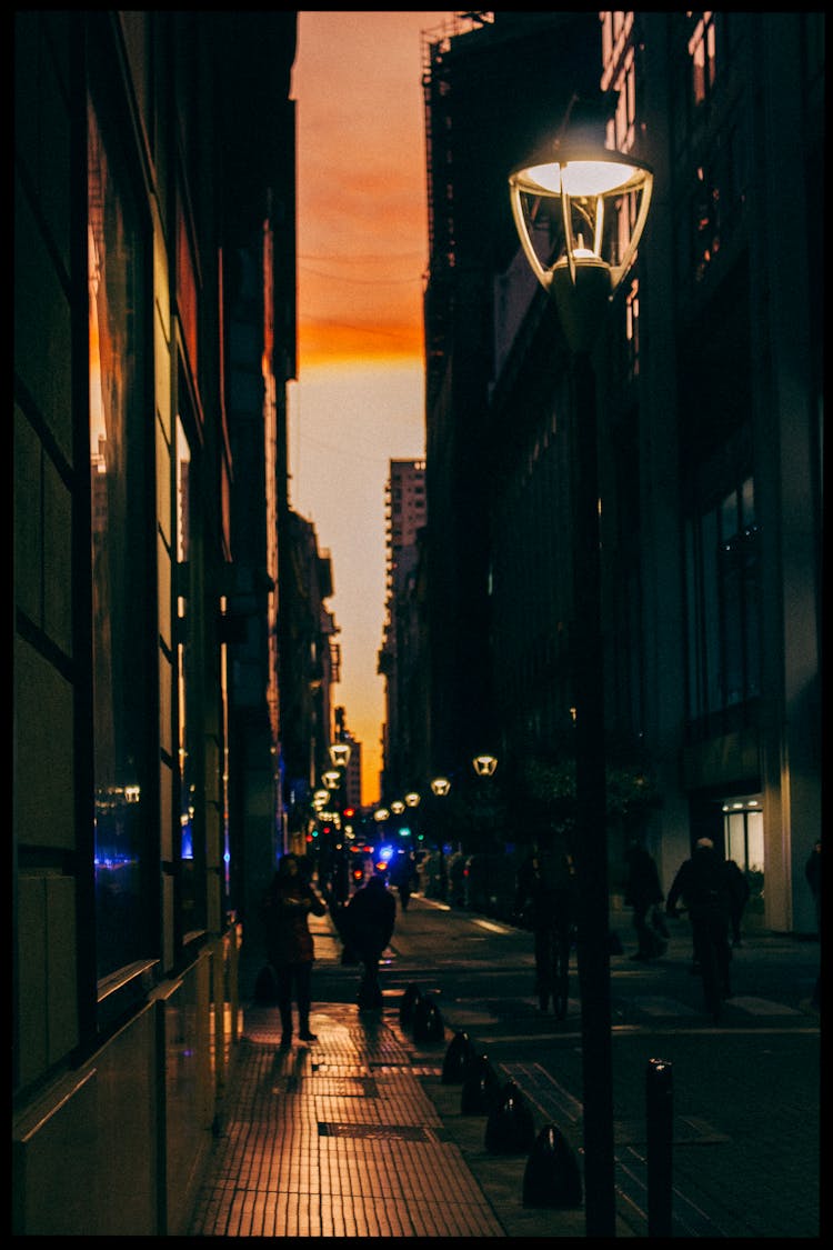 People Walking On A Sidewalk At Night