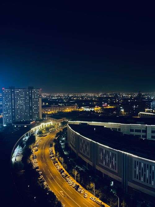 Free Drone shot of a vibrant city at night showcasing illuminated buildings and a curving highway. Stock Photo