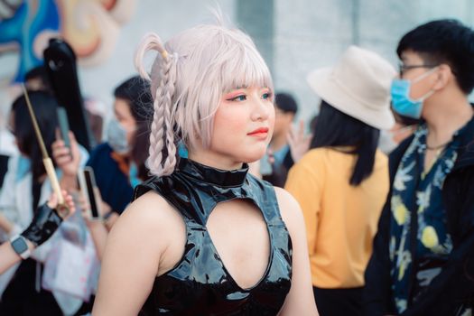 Adult woman in cosplay attire at a vibrant outdoor event, surrounded by people.