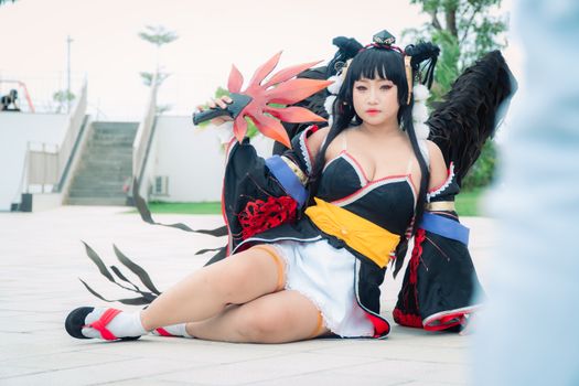 Cosplayer dressed as Nyotengu from Dead or Alive poses outdoors, showcasing elaborate costume.