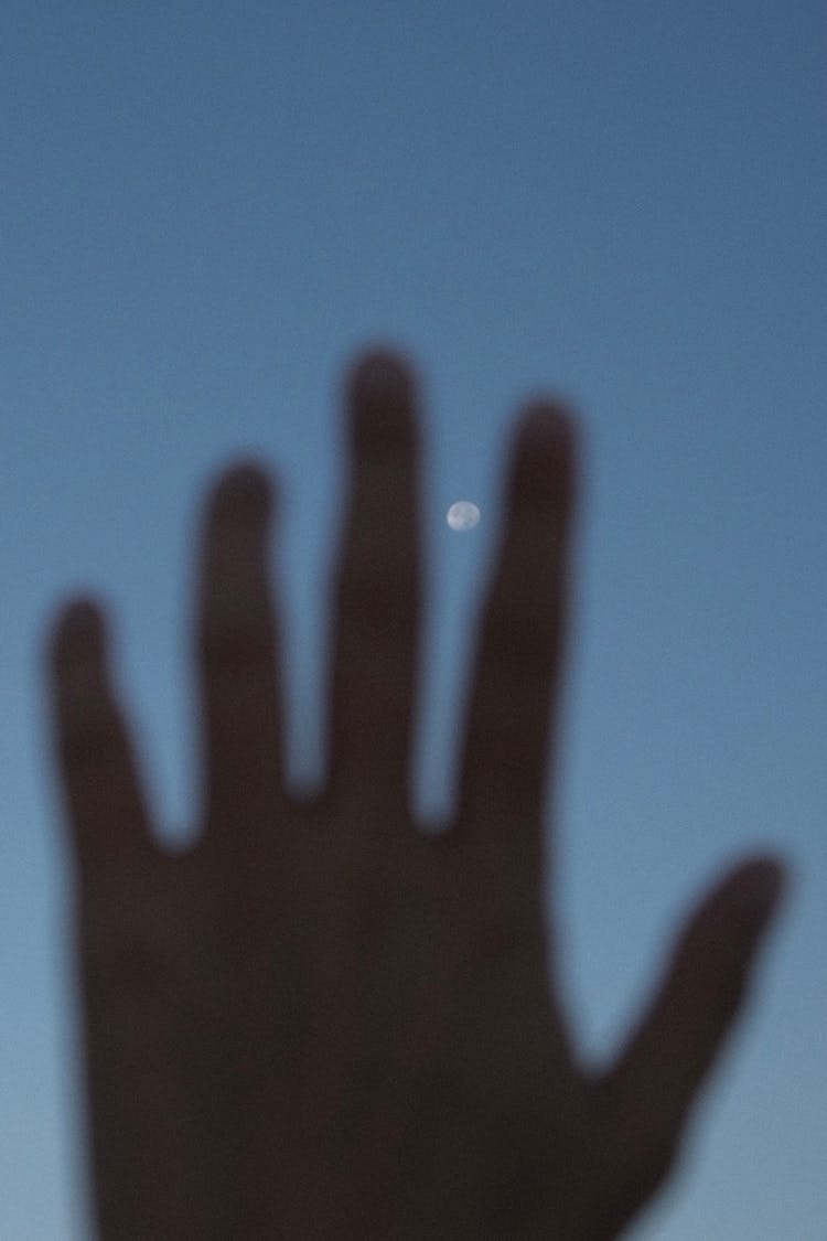 Blurry Picture Of A Hand And The Moon Between Fingers 