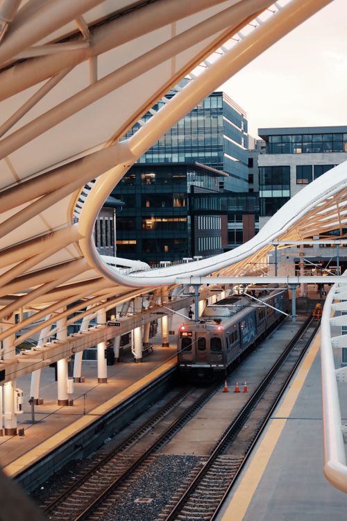 Free A contemporary train station architecture with a moving train and urban backdrop. Stock Photo