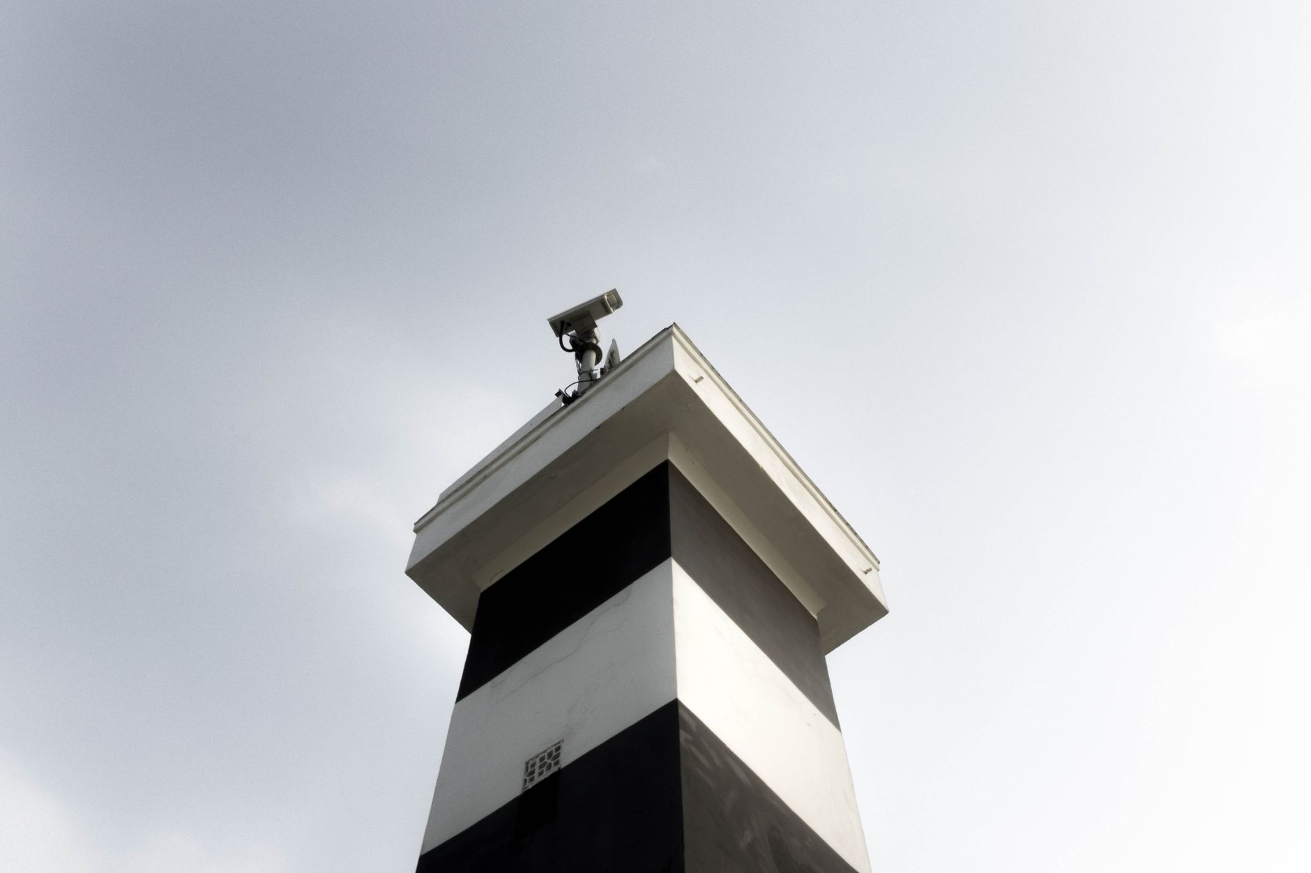 A modern surveillance tower equipped with a CCTV camera against a clear sky, showcasing security and technology.
