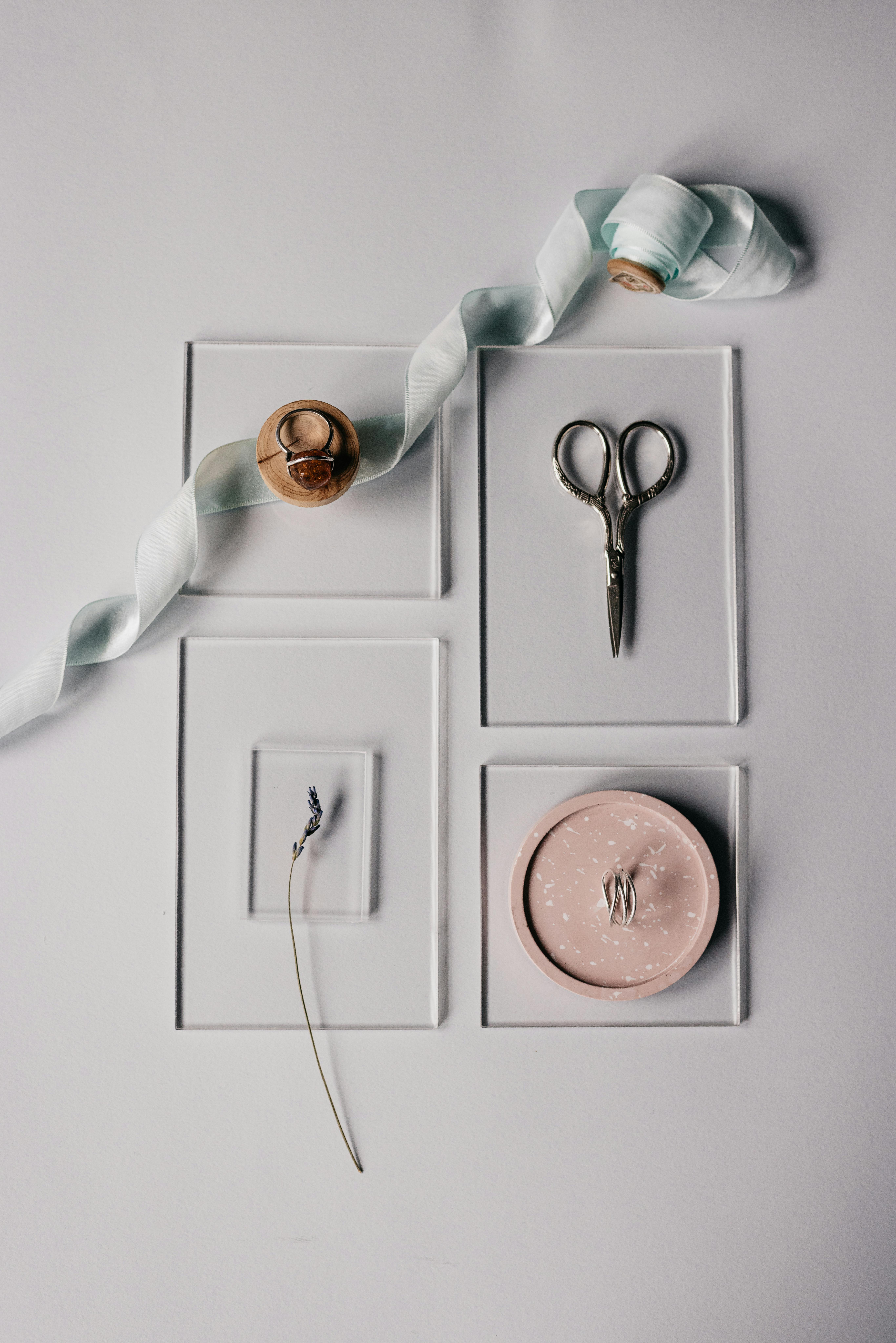 Flat lay of ribbon, lavender, scissors, and ornaments on a minimalist surface.